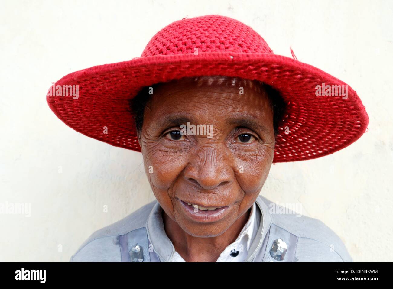 Femme malgache frayeuse avec un chapeau rouge. Portrait. Madagascar. Banque D'Images