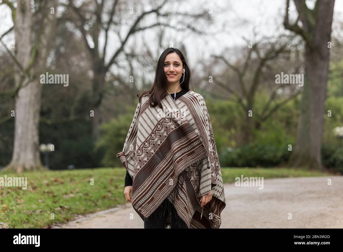 Belle femme indienne portant un poncho souriant à l'appareil photo. Arrière-plan du parc à l'automne. Banque D'Images