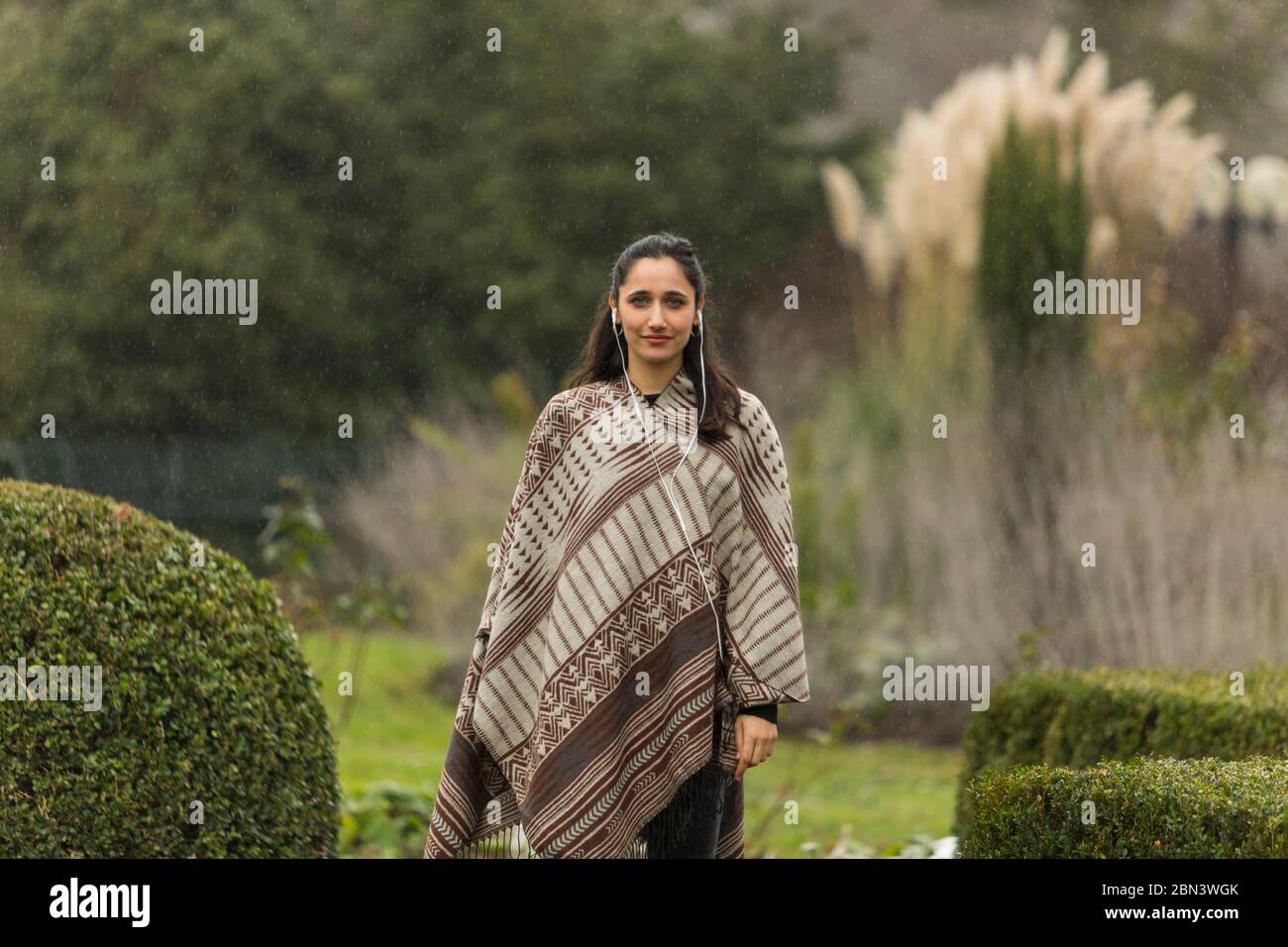 Vue de face d'une femme indienne portant un poncho dans un jardin ornemental. Banque D'Images