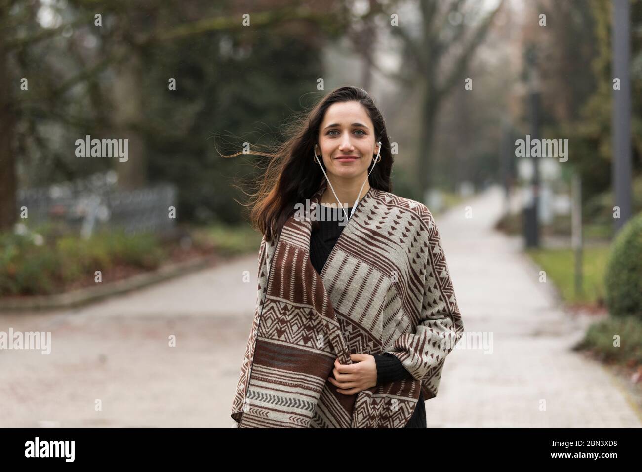 Belle femme indienne portant un poncho souriant en toute confiance à l'extérieur. Regarder la caméra. Banque D'Images