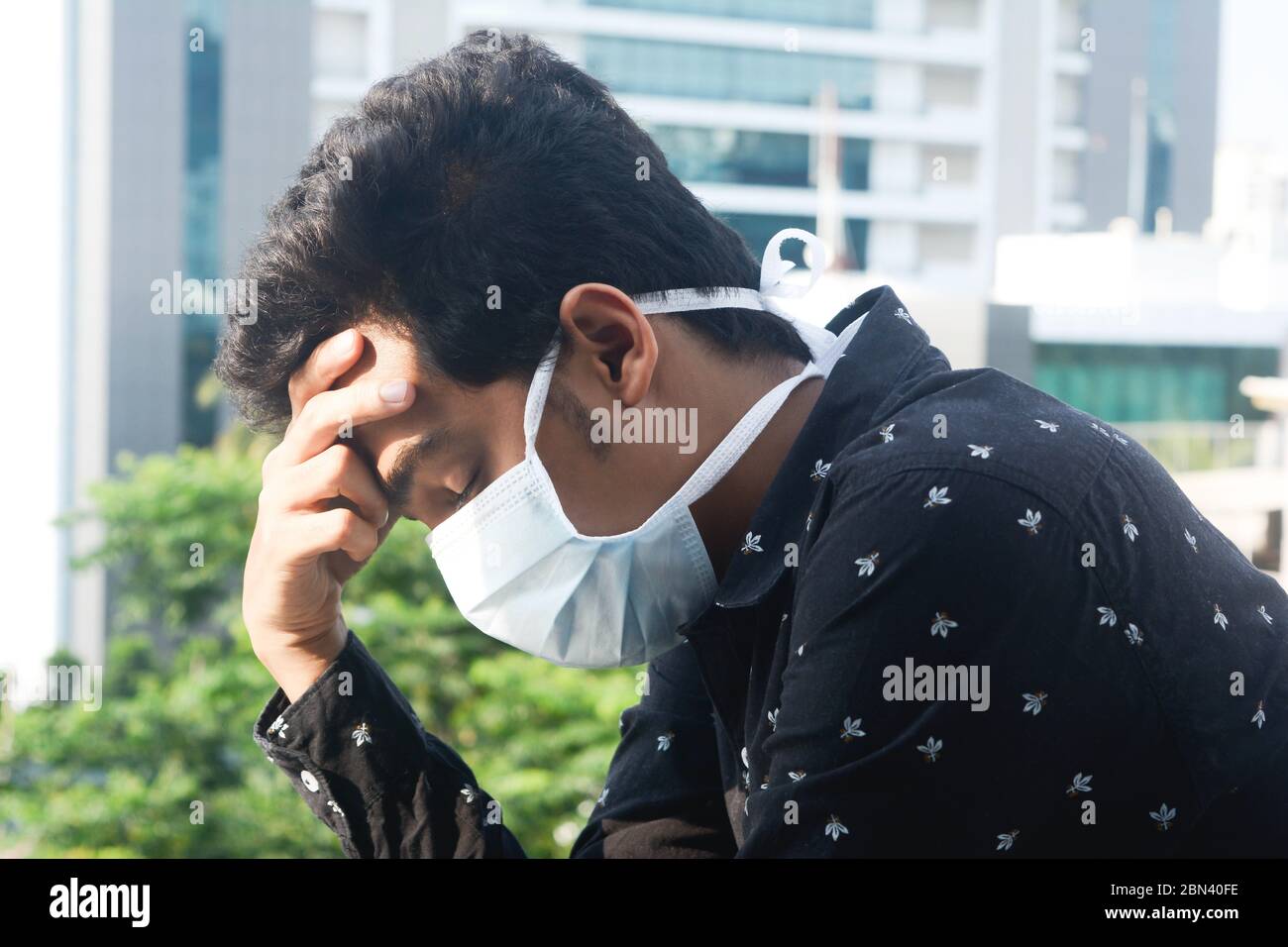 Un jeune homme avec un masque protecteur a un mal de tête de tension. Banque D'Images