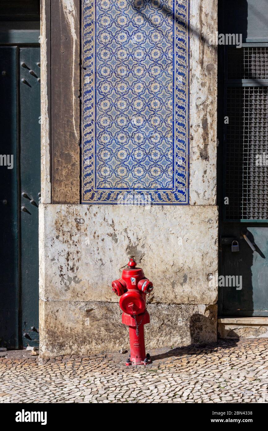 Un poteau incendie rouge se trouve en face d'un mur partiellement carrelé dans une rue de Lisbonne, Portugal Banque D'Images