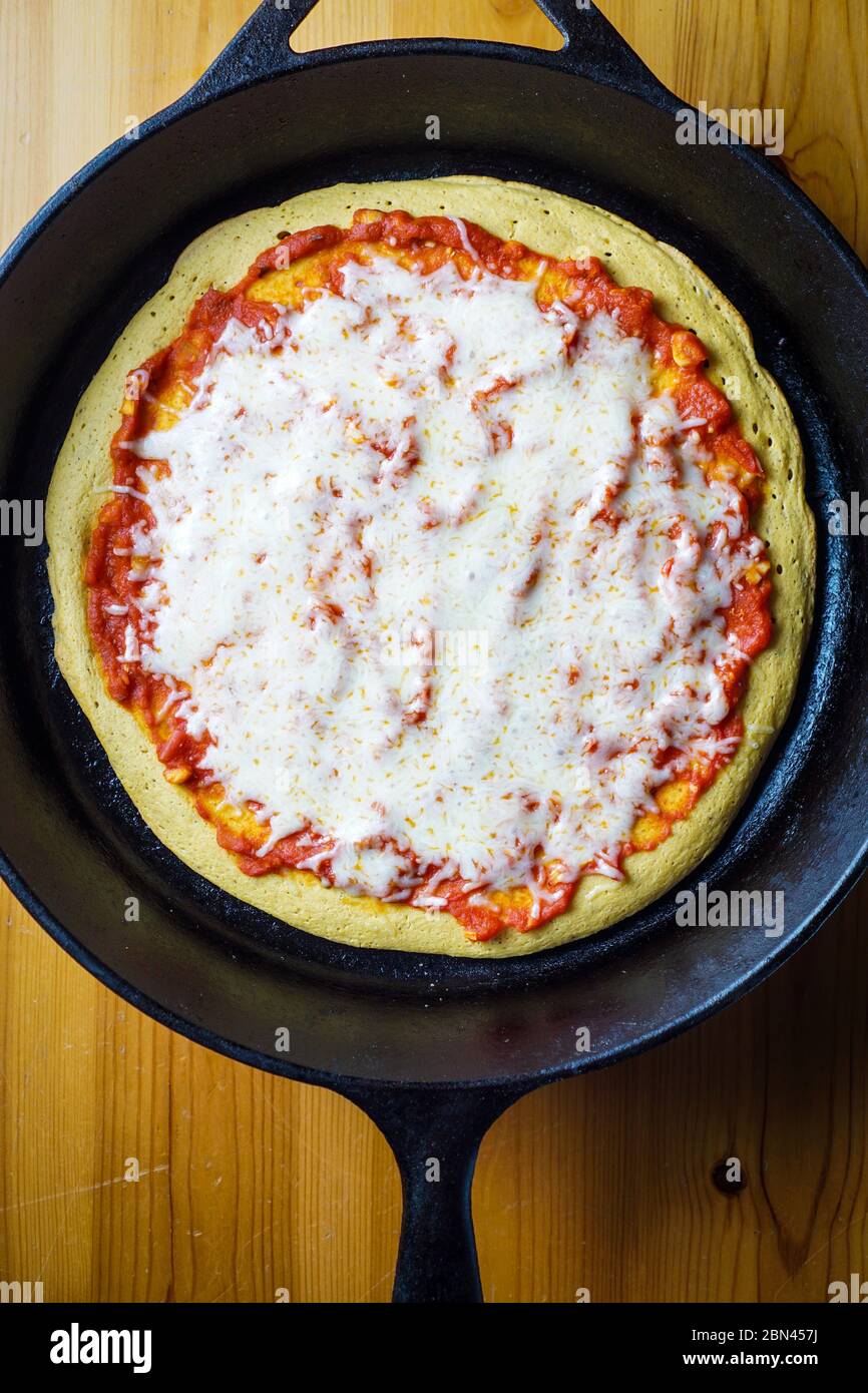 Pizza à croûte de pois chiches dans une poêle en fonte Banque D'Images