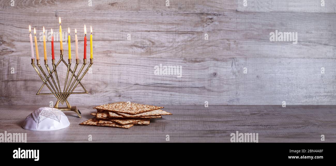 Symboles traditionnels de la célébration de Hanoukkah, de la menorah, du Matzoh et du kippah. Vue latérale. Bannière. Fond en bois clair Banque D'Images