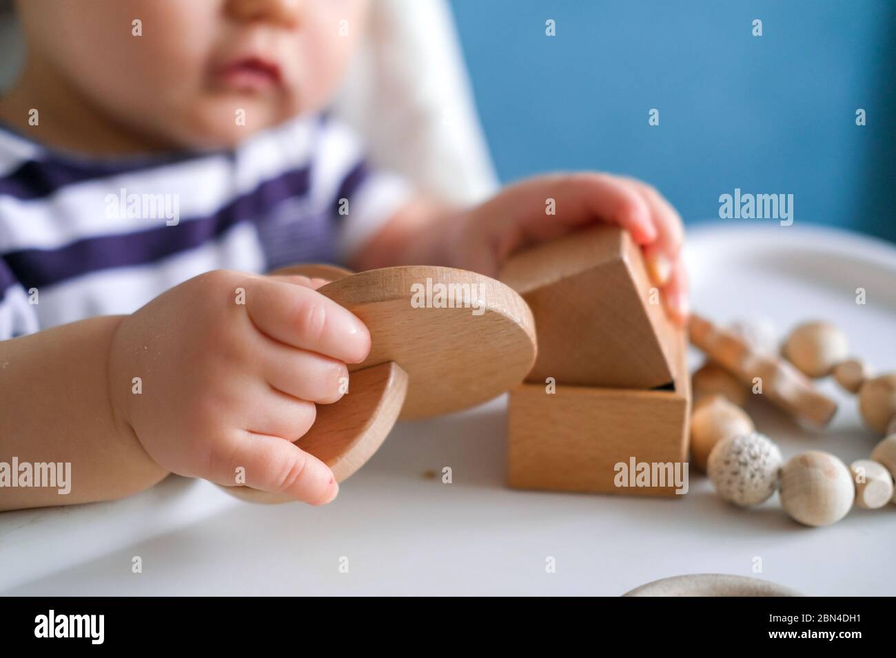 jouets en bois éco. jeu pour bébé. Petit enfant caucasien intelligent  jouant des jouets naturels sur chaise haute. Jeux pour le développement  précoce. Jouet dans les mains des enfants gros plan Photo