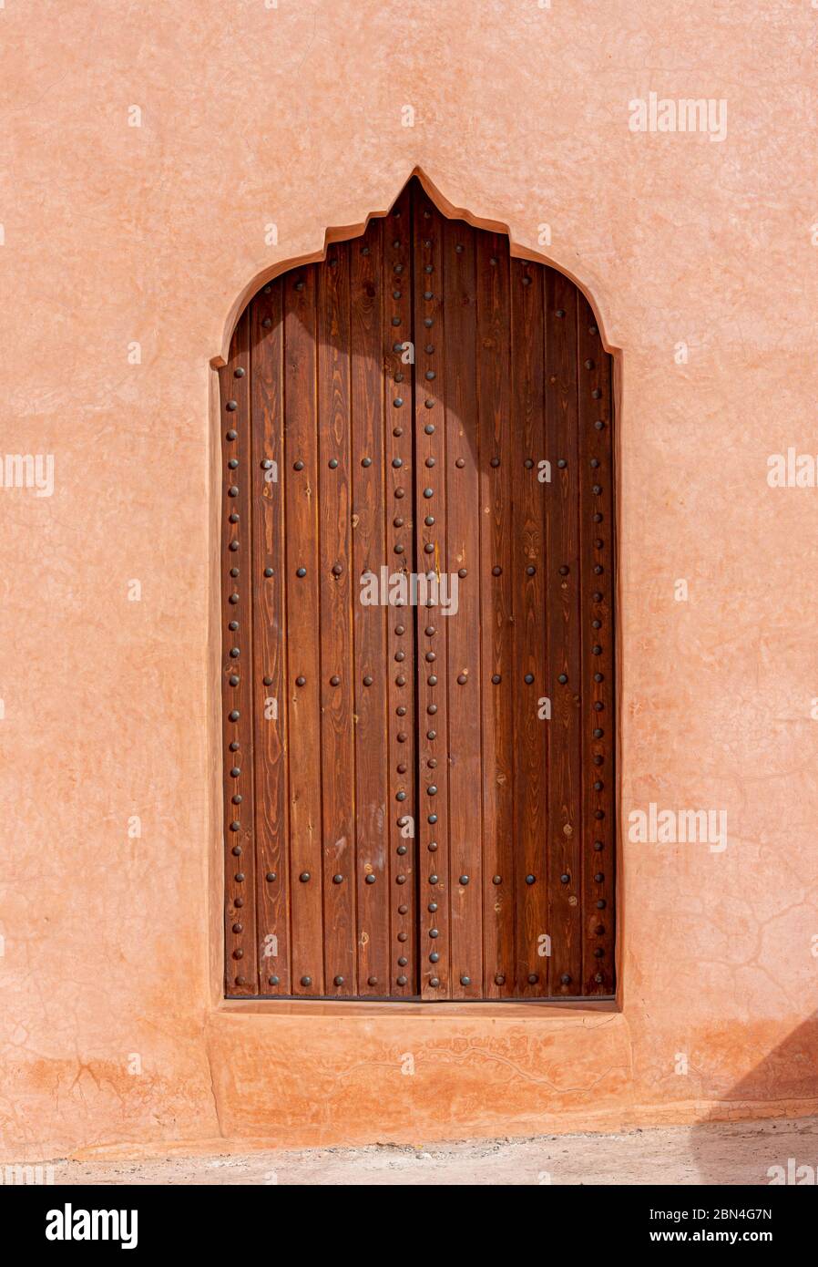 Architecture arabe traditionnelle, porte en bois de style musulman et mur en argile rouge Banque D'Images