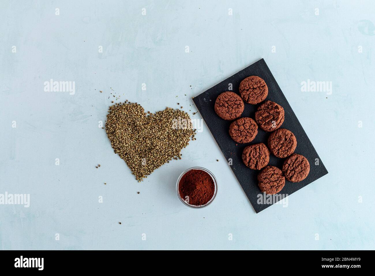 Biscuits au cannabis CBD, cacao et graines de chanvre en forme de coeur sur fond clair. Marijuana médicinale dans les aliments. Banque D'Images