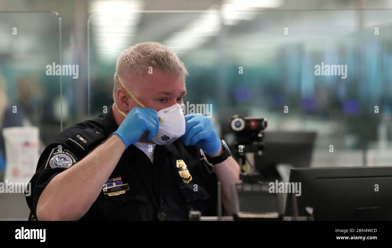 Le 13 mars 2020, un agent des douanes et de la protection des frontières des États-Unis à l’aéroport international de Dulles en Virginie s’est préparé aux arrivées internationales de passagers en portant un respirateur N95 en réponse à la pandémie de COVID-19. Les agents et les passagers du CBP portaient un EPI pour réduire le risque de transmission du virus. Banque D'Images