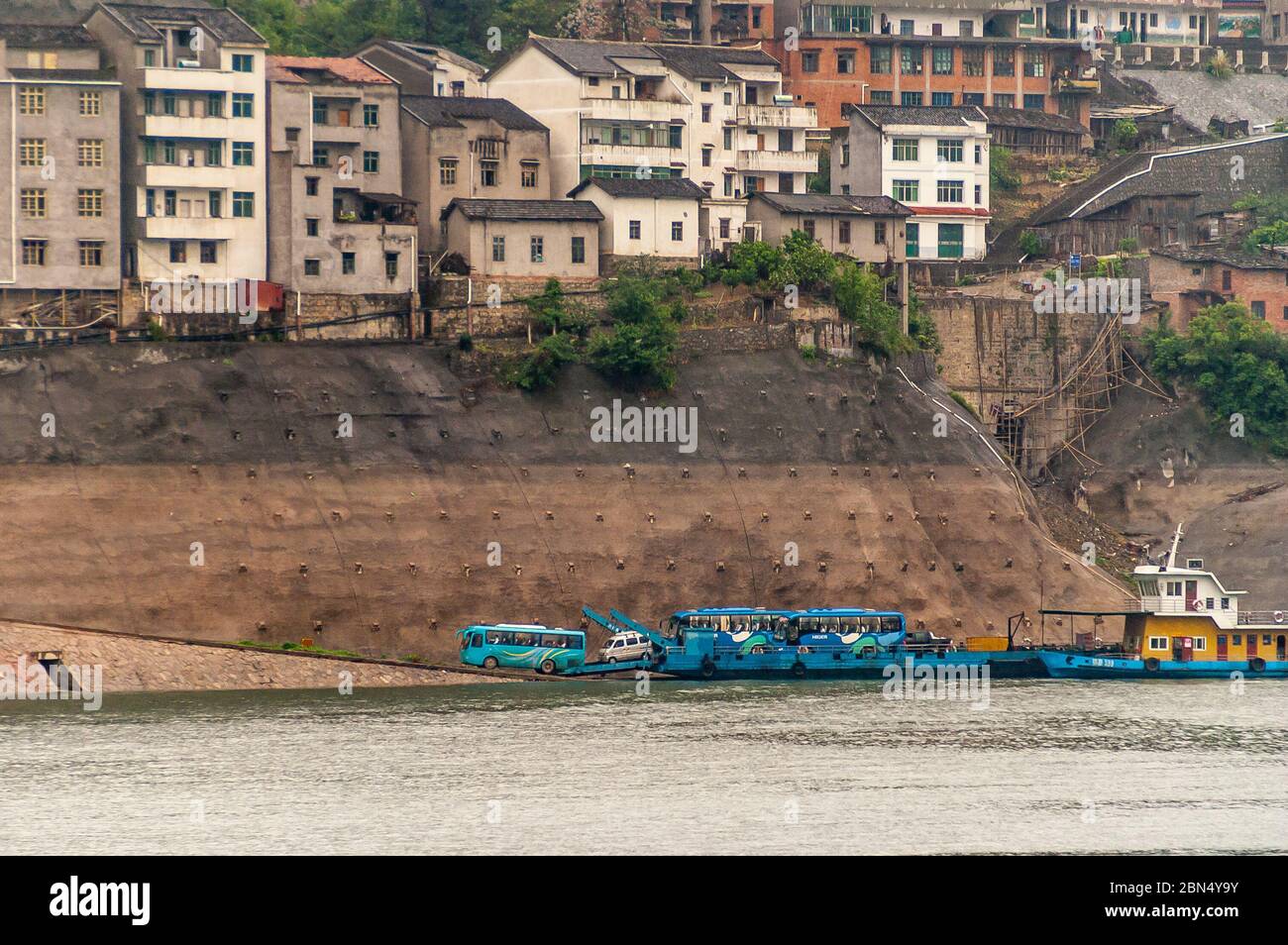 Guizhou, Chine - 6 mai 2010 : gorge de Xiling sur la rivière Yangtze. Gros plan de logements à plusieurs niveaux sur une pente de la ville renforcée de pierres brunes. Ferry et Banque D'Images