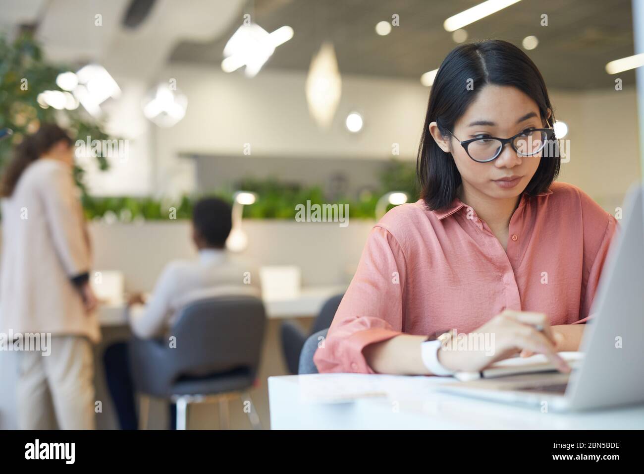 Portrait de la jeune femme asiatique utilisant un ordinateur portable pendant l'étude dans un café, copier l'espace Banque D'Images