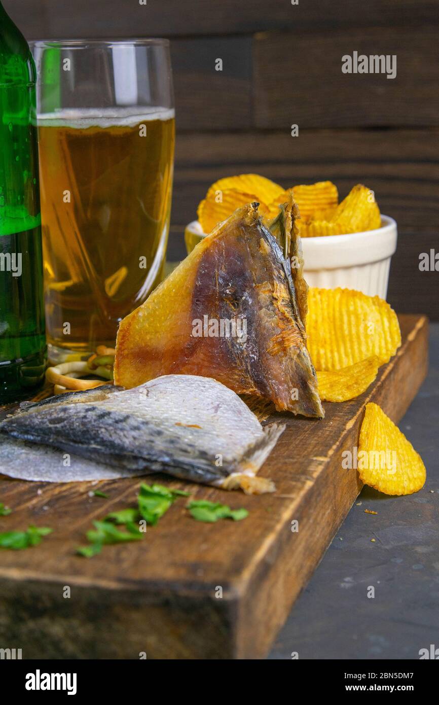 Dorade séchée en forme de papillon avec bière, citron et chips de pomme de terre sur un panneau en bois sombre. En-cas sur le poisson avec de la bière. Gros plan Banque D'Images