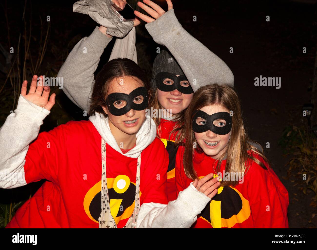 Les filles de l'adolescence portant des costumes Incredibles ayant le plaisir sur Halloween hors trick et de traiter. St Paul Minnesota MN États-Unis Banque D'Images