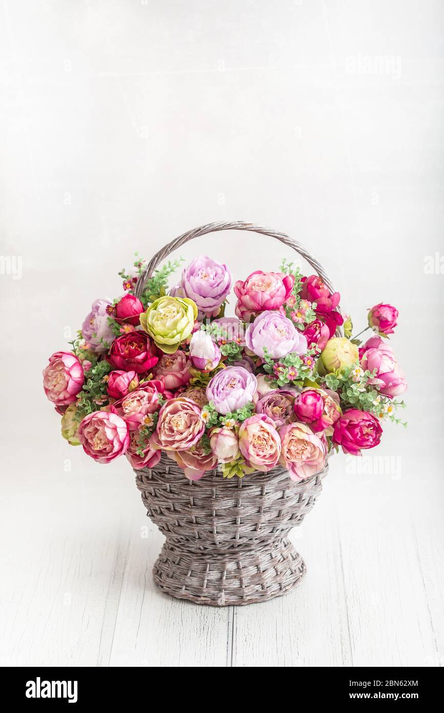Magnifique bouquet de pivoines dans un panier ancien sur parquet Banque D'Images