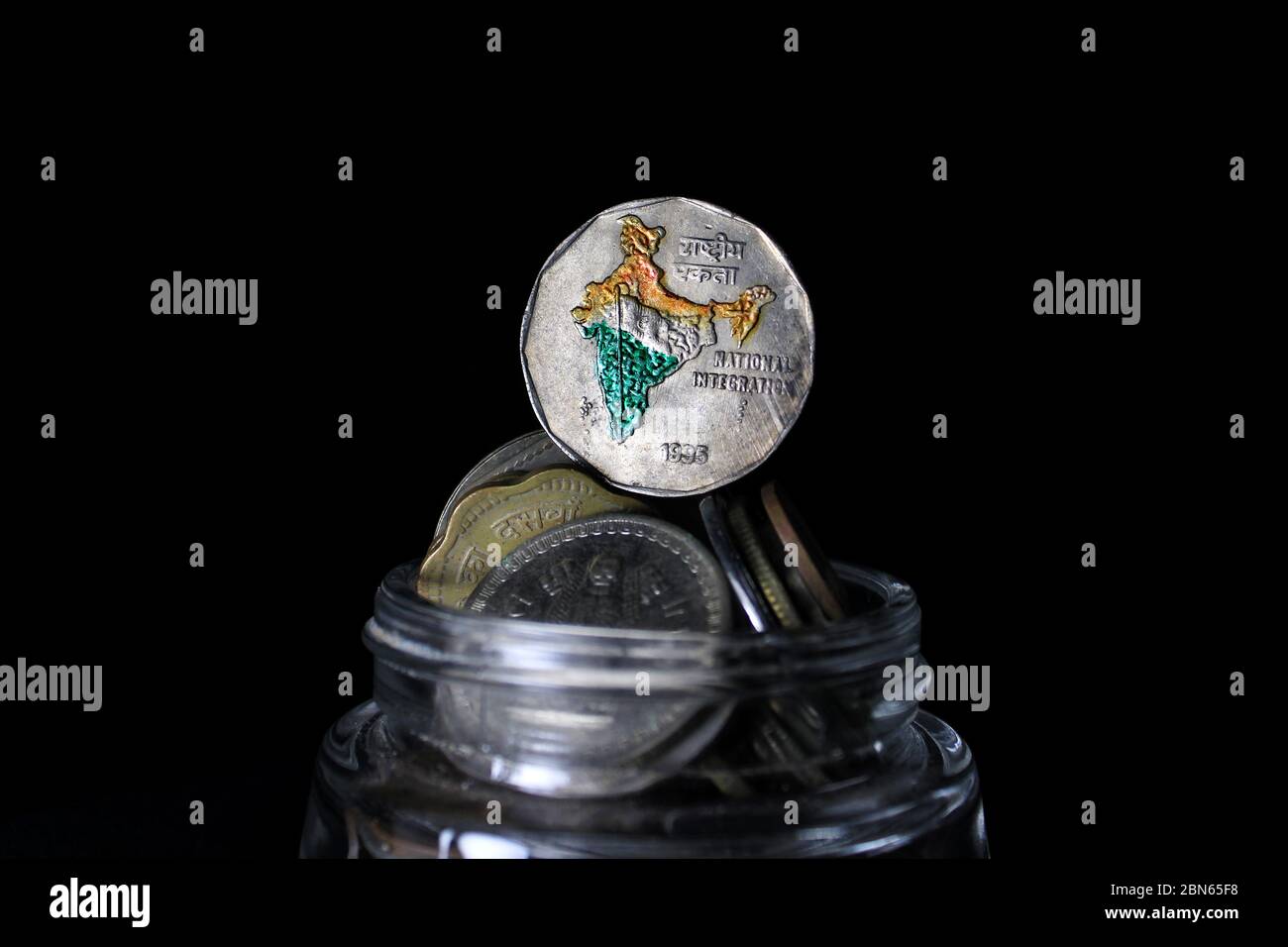 Deux roupies de l'Inde isolées sur fond noir. Carte de l'Inde comme symbole de l'intégration nationale indienne représentée dans les pièces de monnaie indiennes. Banque D'Images