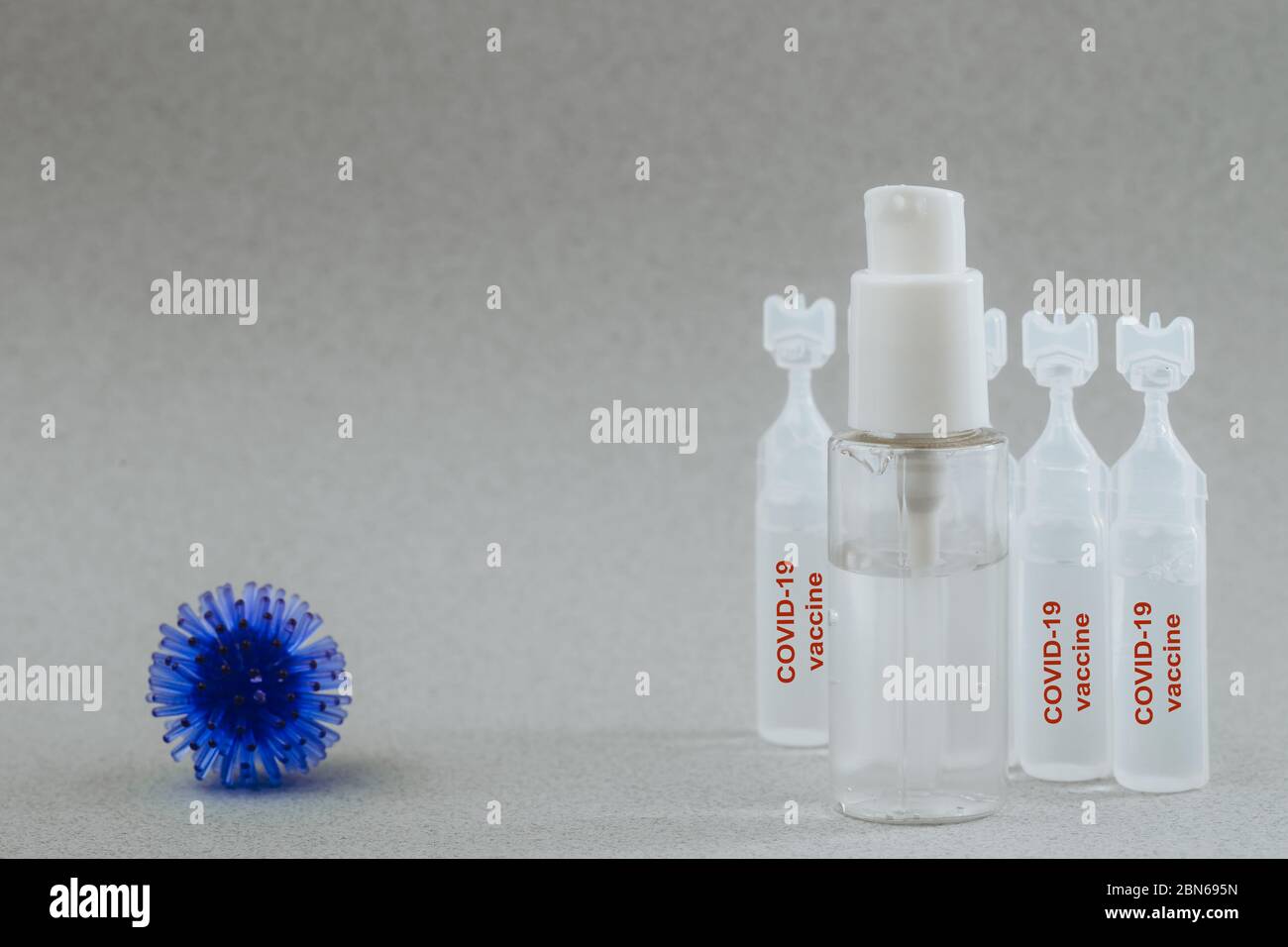 Modèle abstrait du coronavirus, ampoule avec médicament et flacon avec gel antibactérien pour les mains sur fond gris. L'ampoule indique Covid-19. Risque de pandémie Banque D'Images