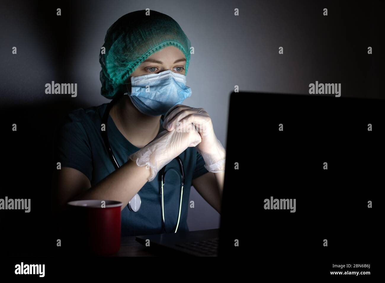 Femme caucasienne médecin infirmière dans le masque chirurgical semble fatigué, épuisé la nuit à cause de covid Banque D'Images