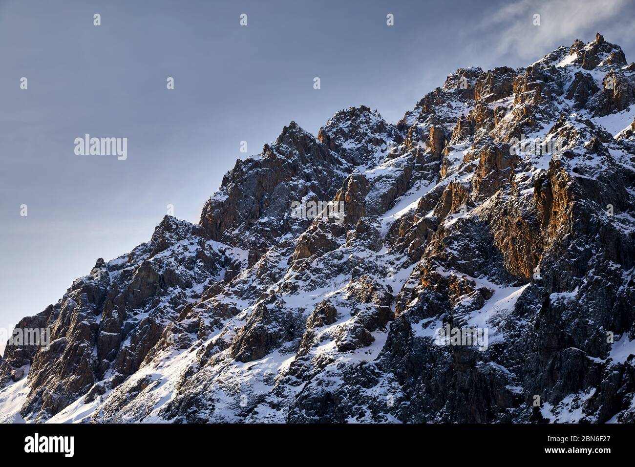 Lever du Soleil à de hautes montagnes avec de la neige sur fond de ciel bleu à l'heure d'hiver au Kazakhstan Banque D'Images