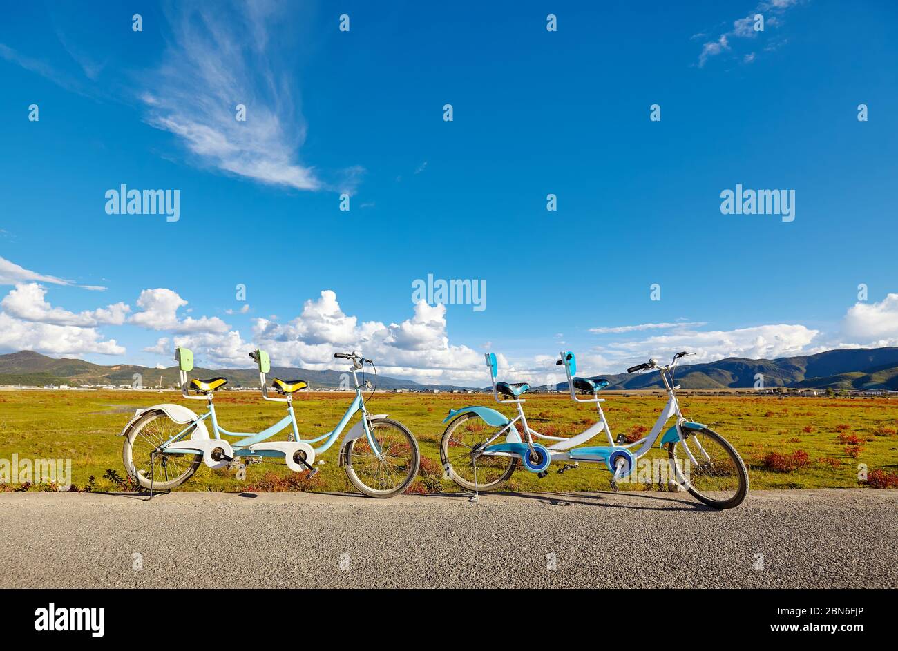 Deux vélos tandem par une route de campagne sur un concept de vacances d'été actif, ensoleillé. Banque D'Images