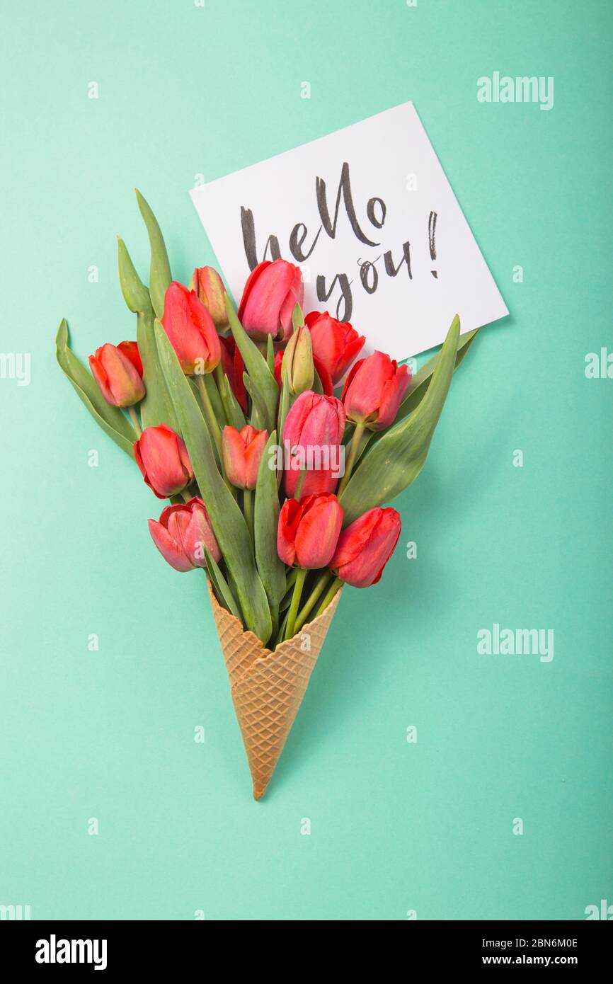 Rouge magnifiques tulipes dans un cône de gaufre de glace avec carte Love You MOM sur un fond bleu de couleur. Idée conceptuelle d'un cadeau de fleur. Ambiance printanière Banque D'Images