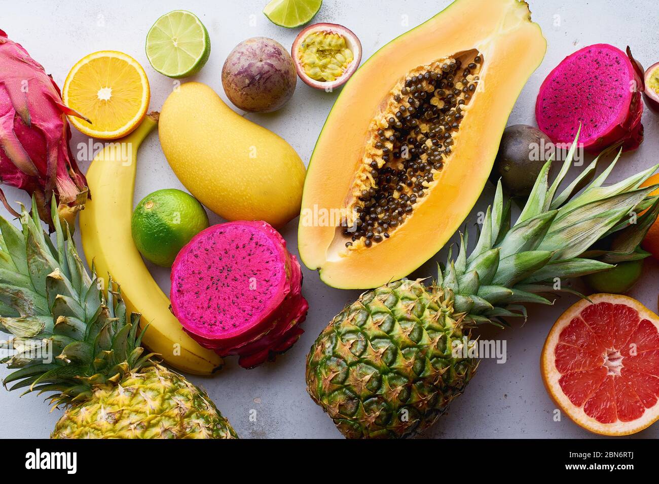 Les fruits tropicaux sont accompagnés de mangue, papaye, pitahaya, fruits de la passion, raisins, limettes et ananas. Table avec ingrédients pour les collations d'été sur béton Banque D'Images