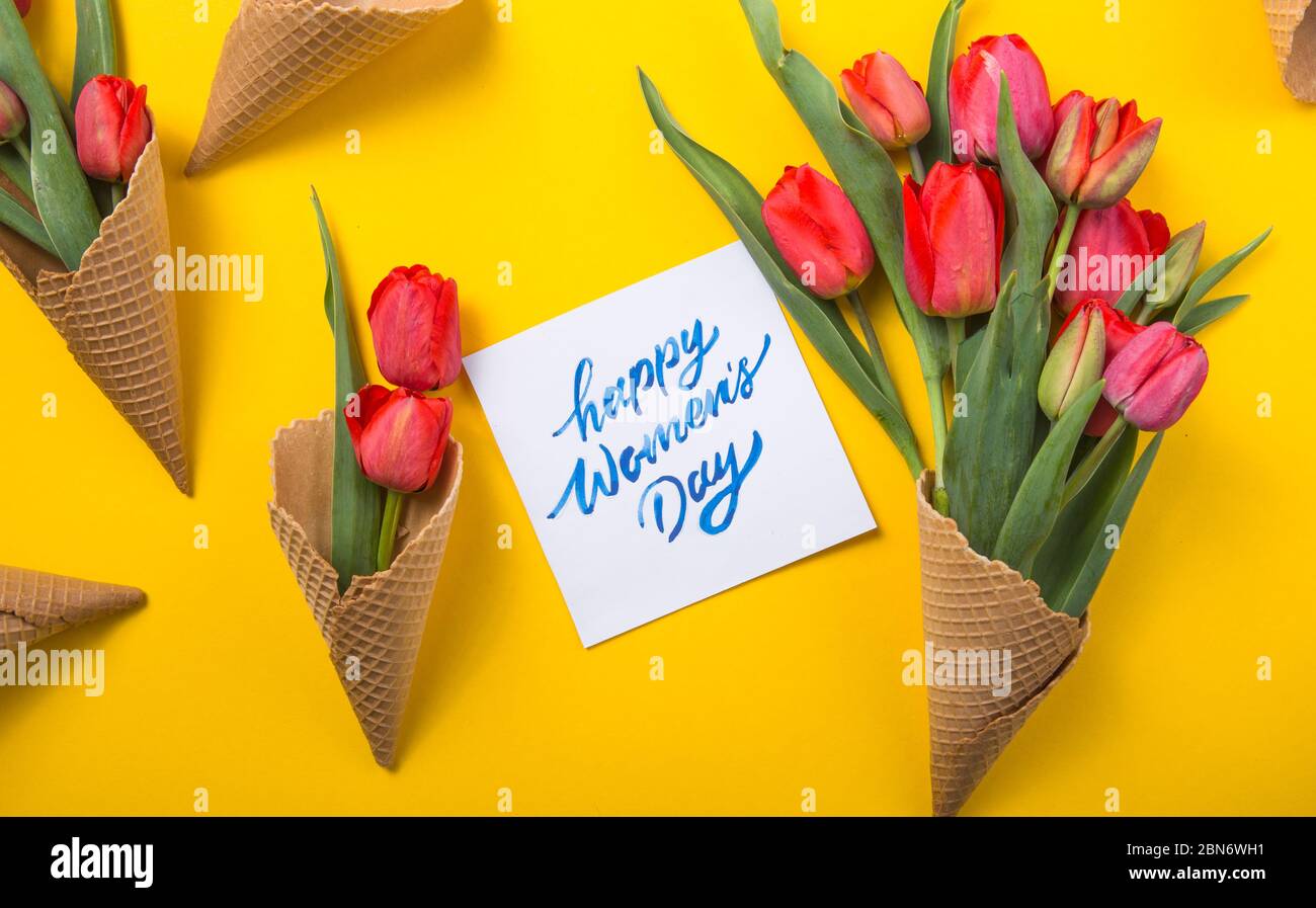 rouge magnifiques tulipes dans un cône de gaufre de glace avec carte d'encre un fond jaune. Idée conceptuelle d'un cadeau de fleur. Ambiance printanière Banque D'Images