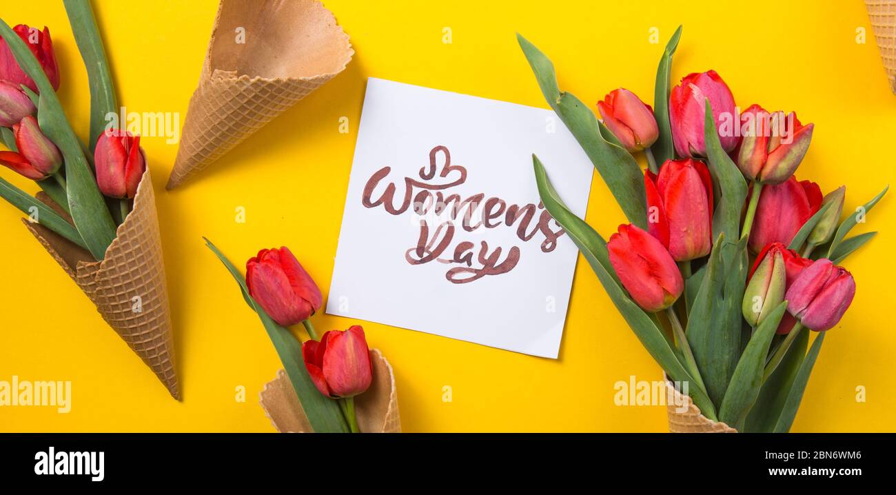rouge magnifiques tulipes dans un cône de gaufre de glace avec carte d'encre un fond jaune. Idée conceptuelle d'un cadeau de fleur. Ambiance printanière Banque D'Images