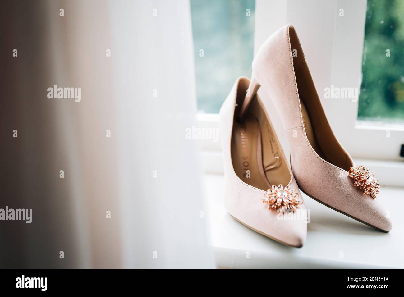 Chaussures de mariage de mariée dans le rebord de fenêtre pendant les préparatifs du matin. Photographie de mariage britannique Banque D'Images