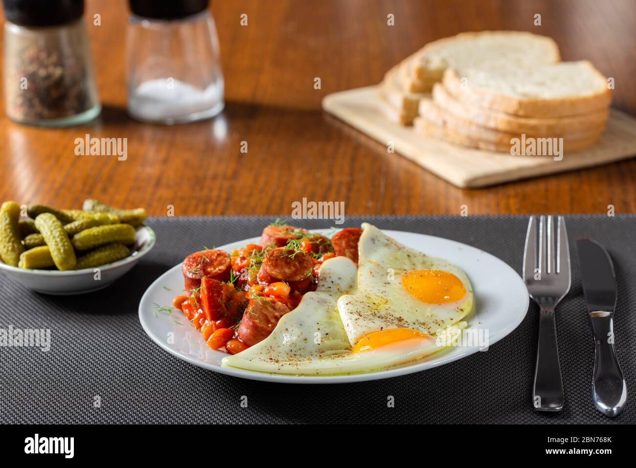 Œufs frits avec des haricots et des saucisses de porc sur une table en bois Banque D'Images