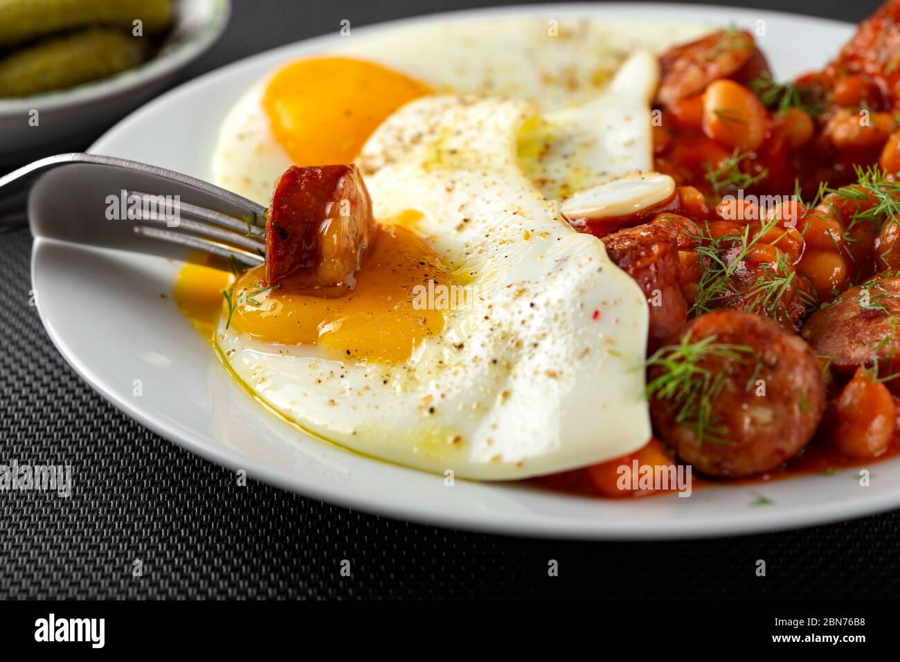 Manger des œufs frits avec des haricots et des saucisses de porc - vue rapprochée Banque D'Images