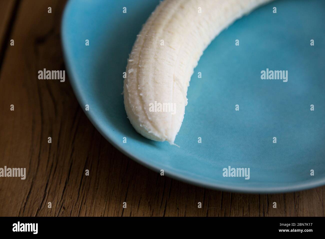 banane pelée à l'intérieur d'une assiette bleue sur une table en bois prête  à manger Photo Stock - Alamy