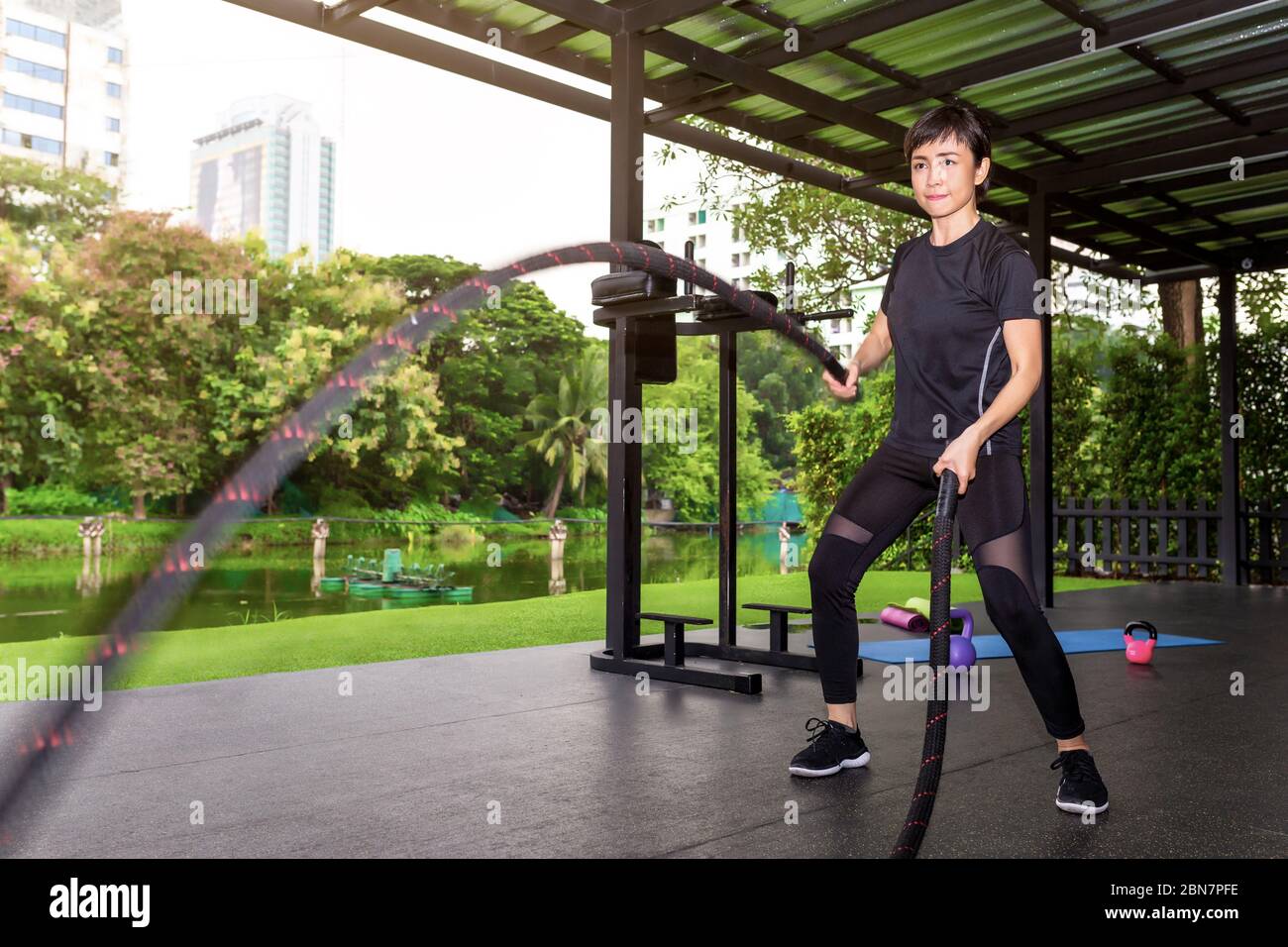 Femme asiatique avec corde de bataille cordes de bataille exercice dans la salle de fitness. Banque D'Images