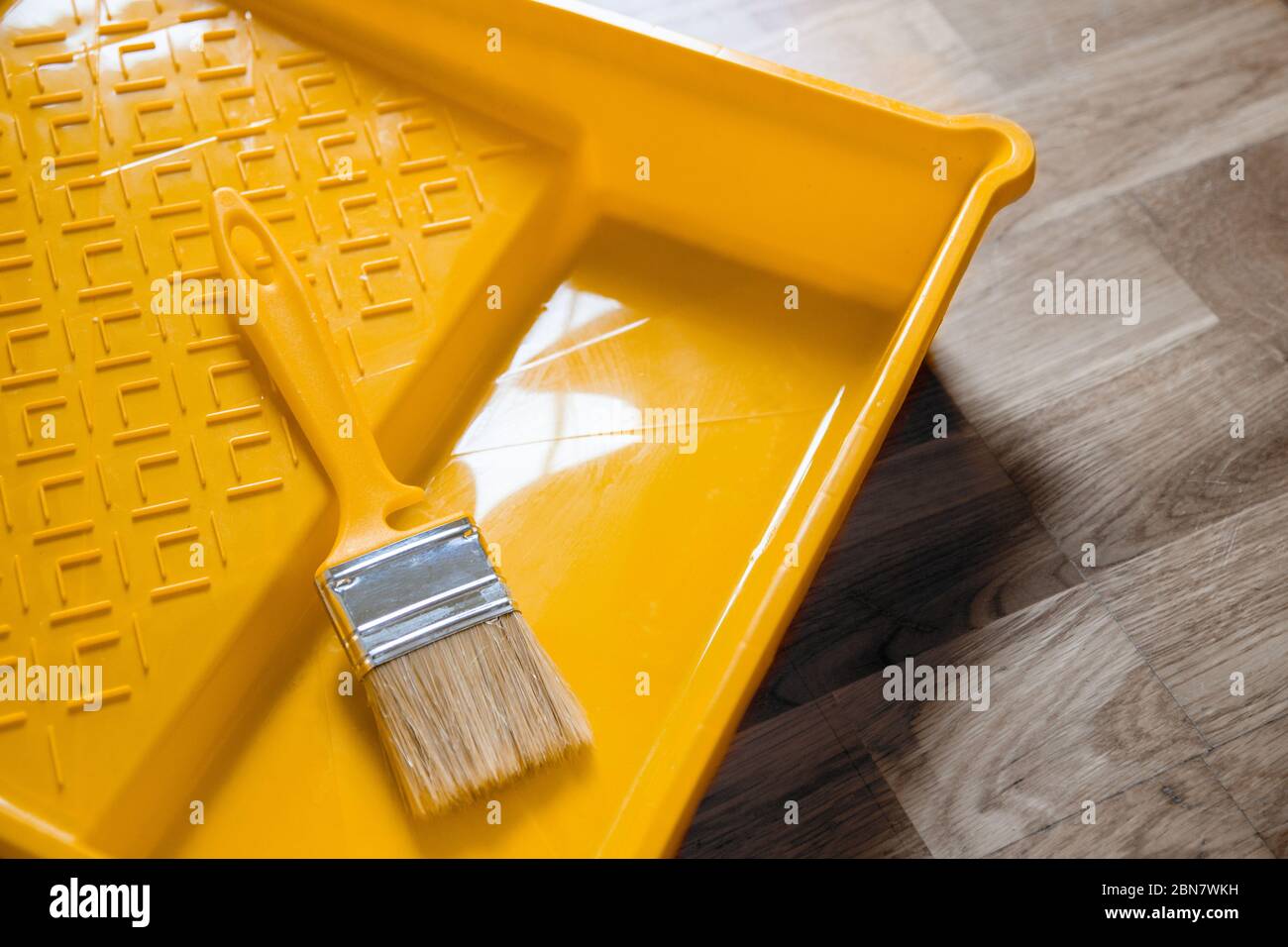 Plateau jaune avec une brosse pour peindre le mur. Bricolage réparation pendant le séjour à la maison concept Banque D'Images