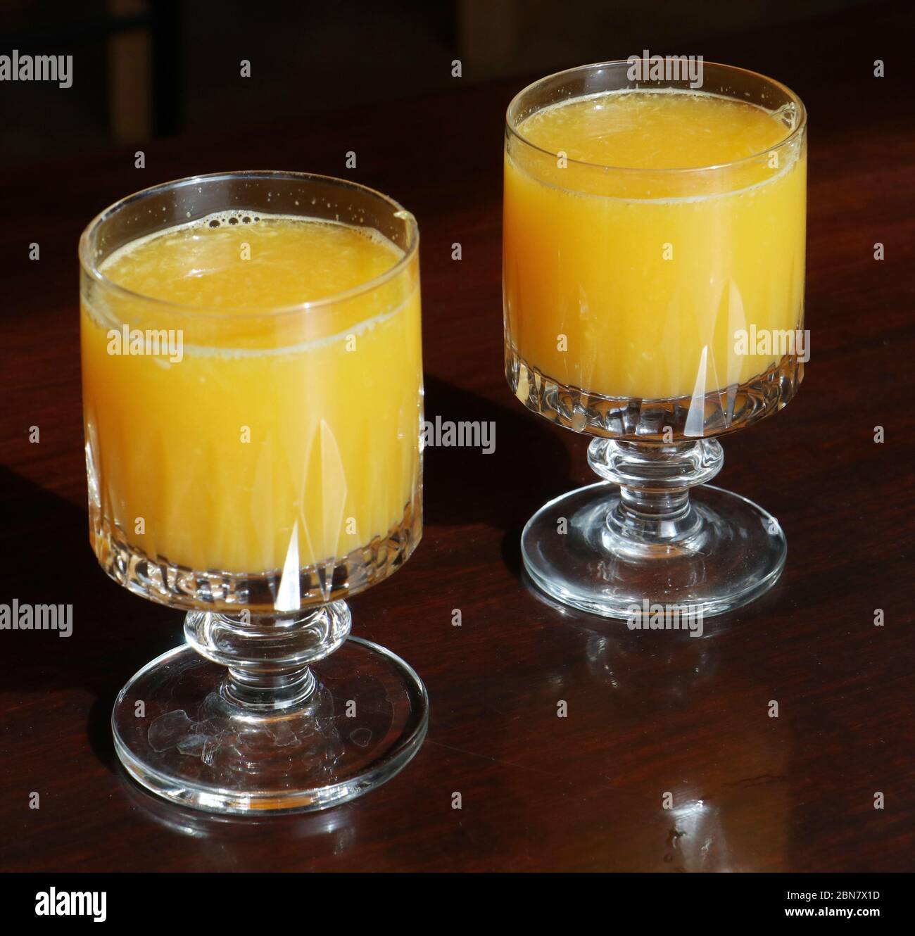 La nourriture reste vie: Deux verres en cristal avec du jus d'orange pressé frais sur une table en bois Banque D'Images