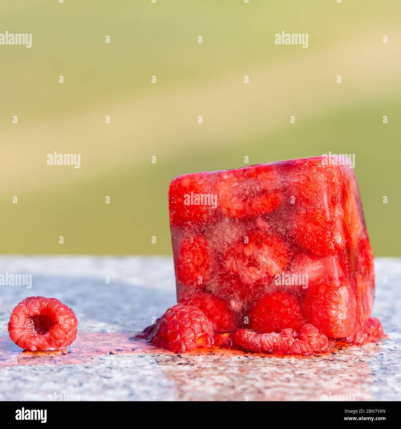 Cube de framboise congelé rouge près de framboise fraîche. Photo créative. Copier l'espace. Banque D'Images