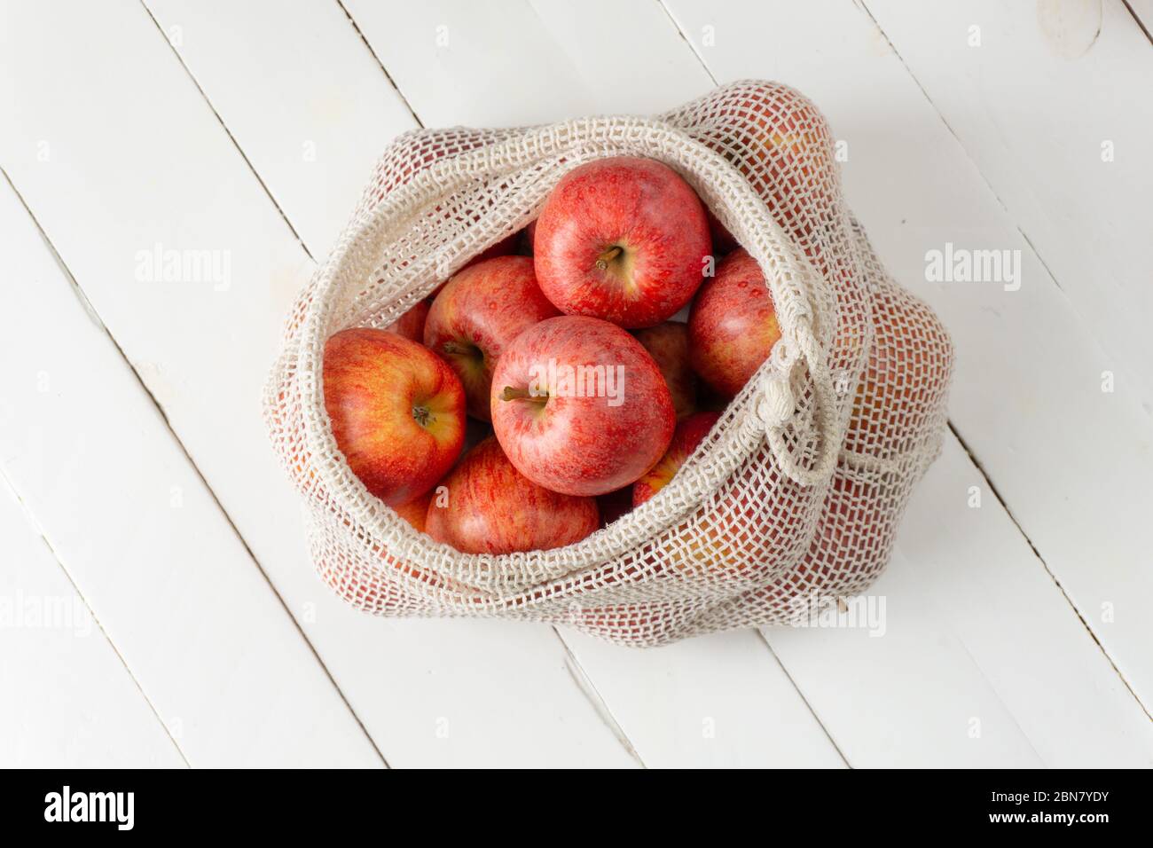 Pommes en sac écologique sur fond de bois blanc. Concept de style de vie sans gaspillage, écologique ou sans plastique. Banque D'Images