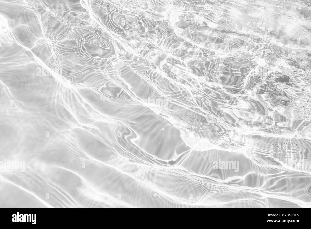 Gros plan de la texture de surface d'eau brute transparente désaturée avec éclaboussures et bulles. Arrière-plan tendance de la nature abstraite. Banque D'Images