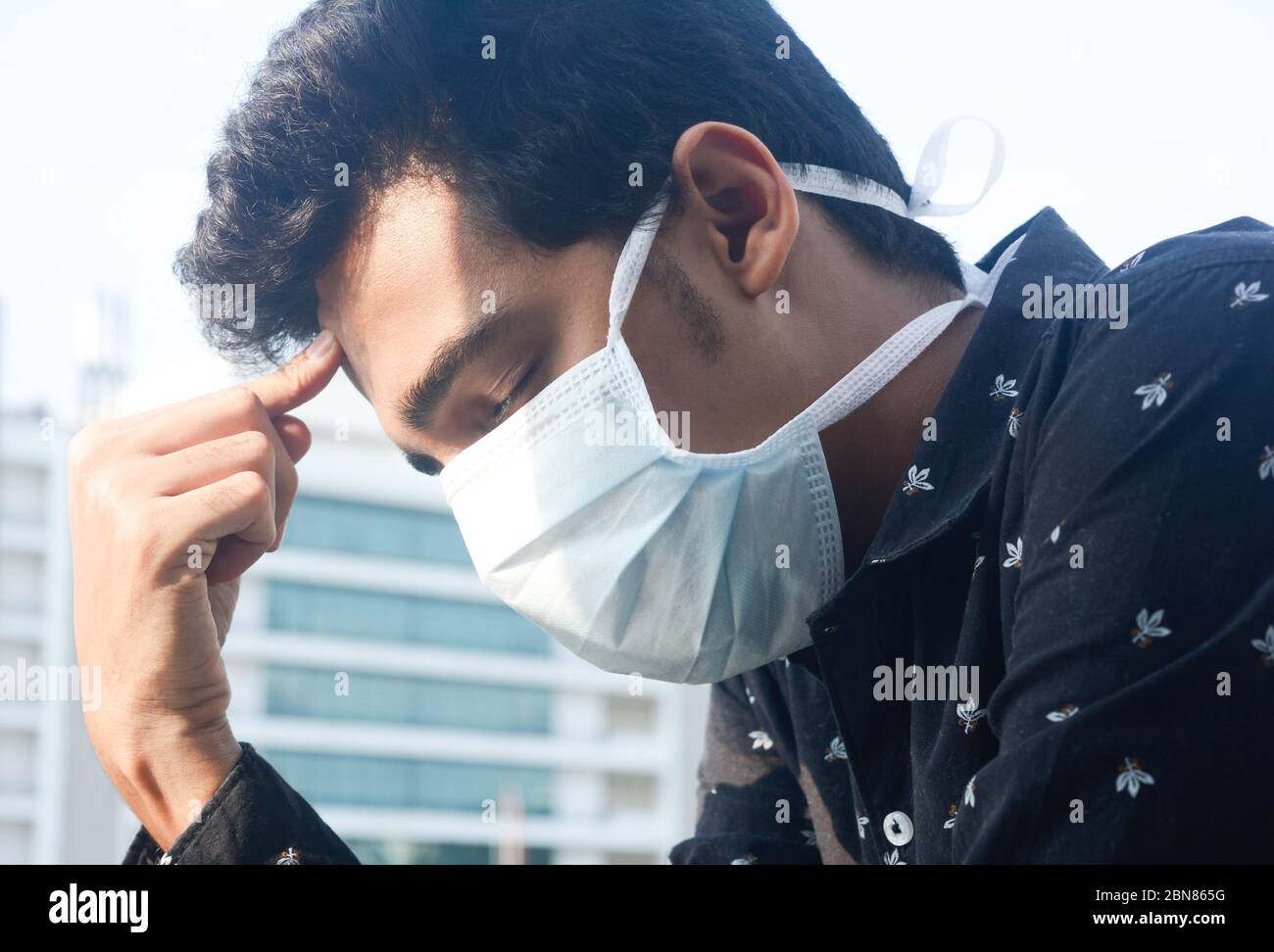 Jeune homme portant un masque de visage pensant comment résoudre le puzzle de virus corona. Banque D'Images