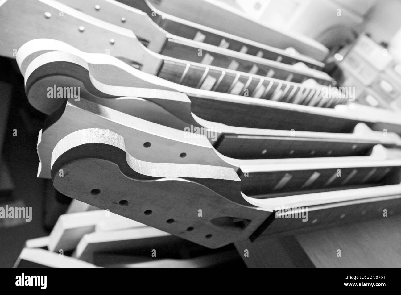 De belles guitares électriques à différents stades de construction montrant des cols, des ramasseurs, des têtes de machines et des boutons de volume. Banque D'Images