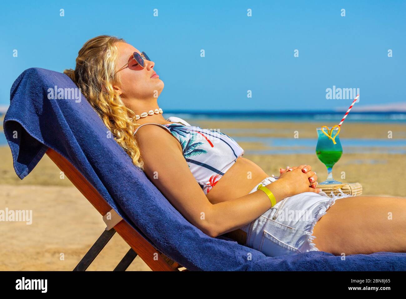 Jeune femme caucasienne bronze sur un lit de plage près de la mer égyptienne Banque D'Images