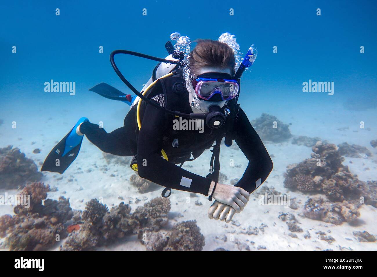 Jeune plongeur caucasien flottant sous l'eau dans la mer bleue Banque D'Images
