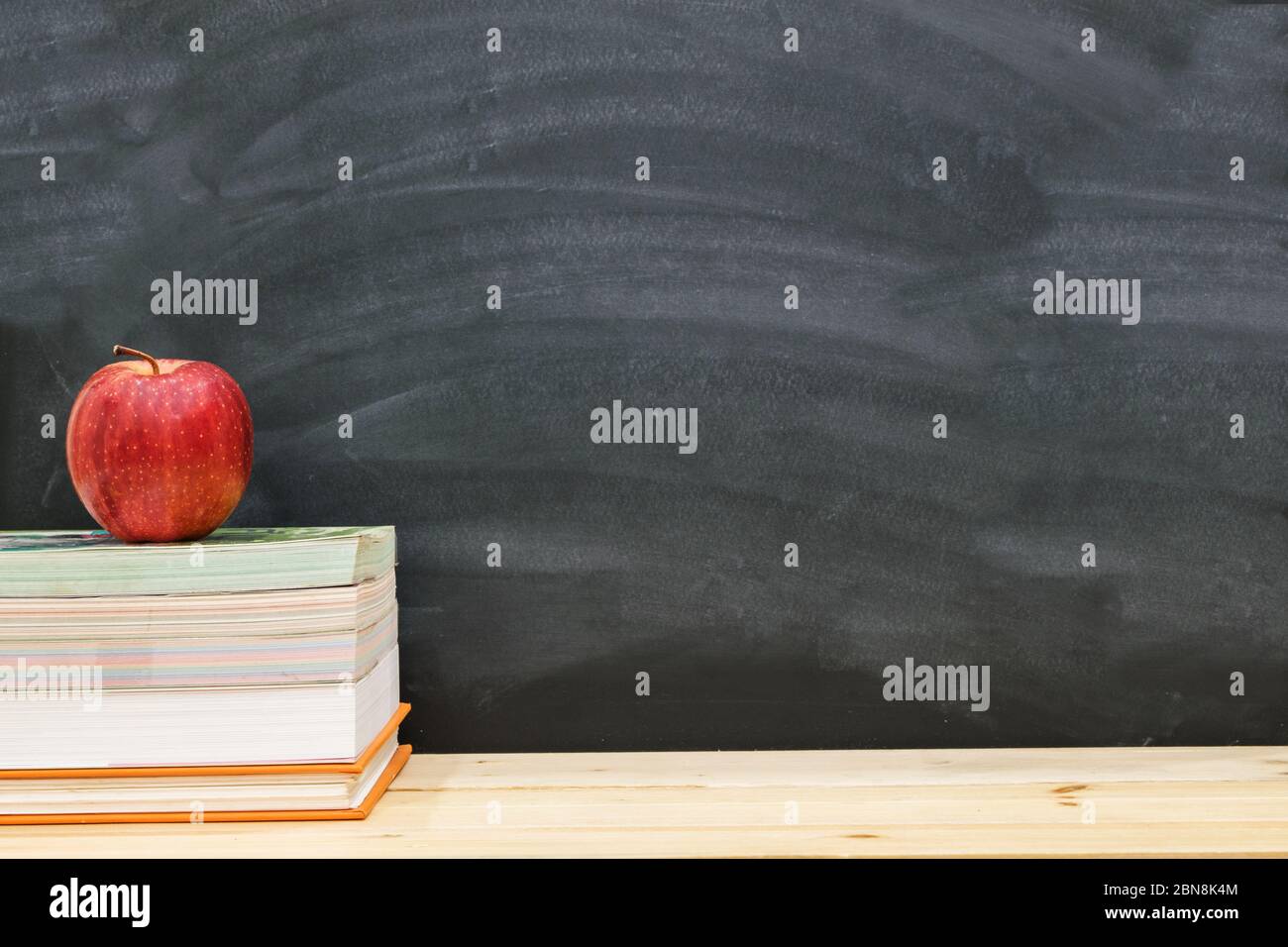 Pomme rouge reposant sur le livre avec tableau noir comme fond, retour à l'école concept. Banque D'Images