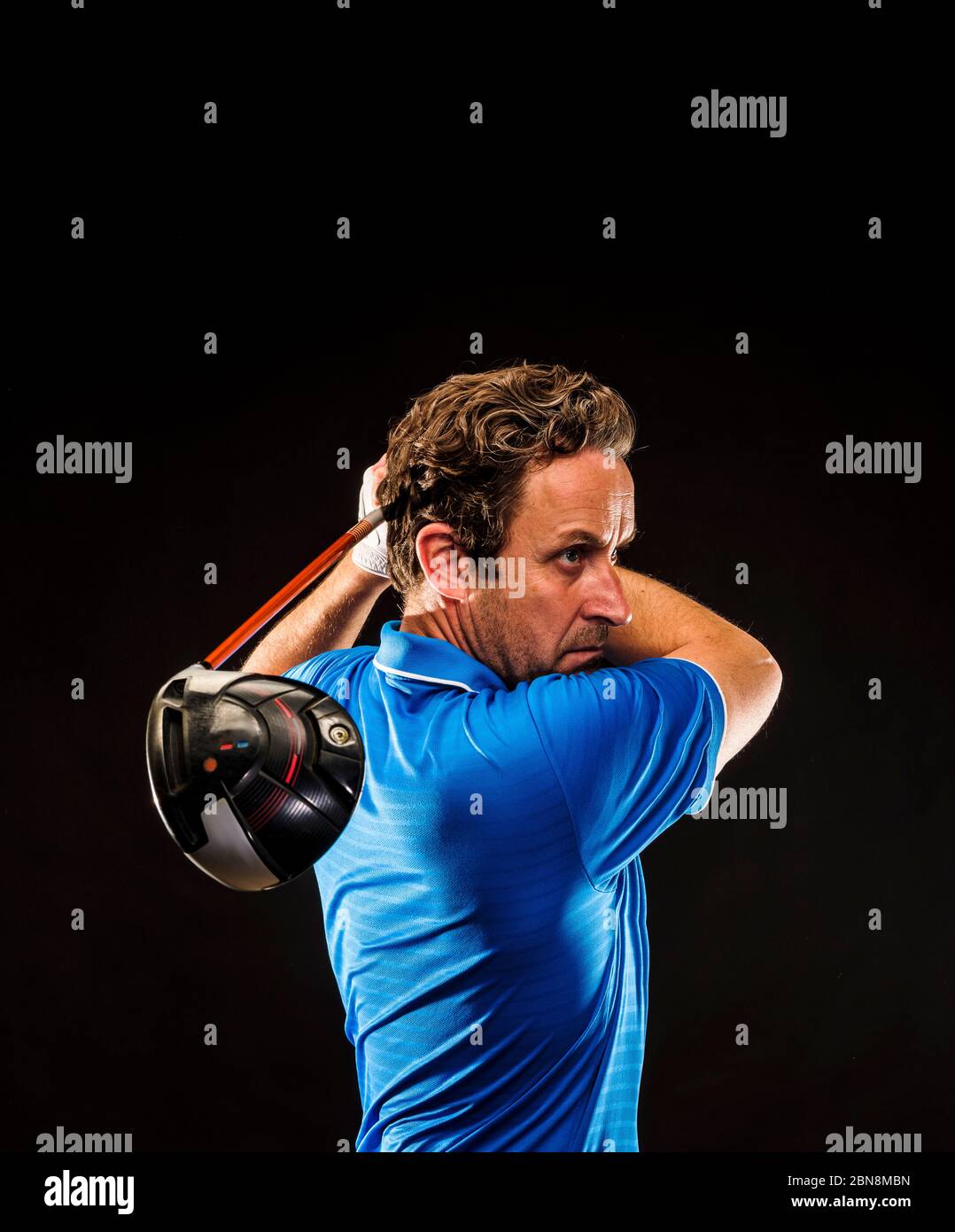 Portrait d'un joueur de golf perfectionnant l'oscillation isolée sur fond sombre, image verticale Banque D'Images