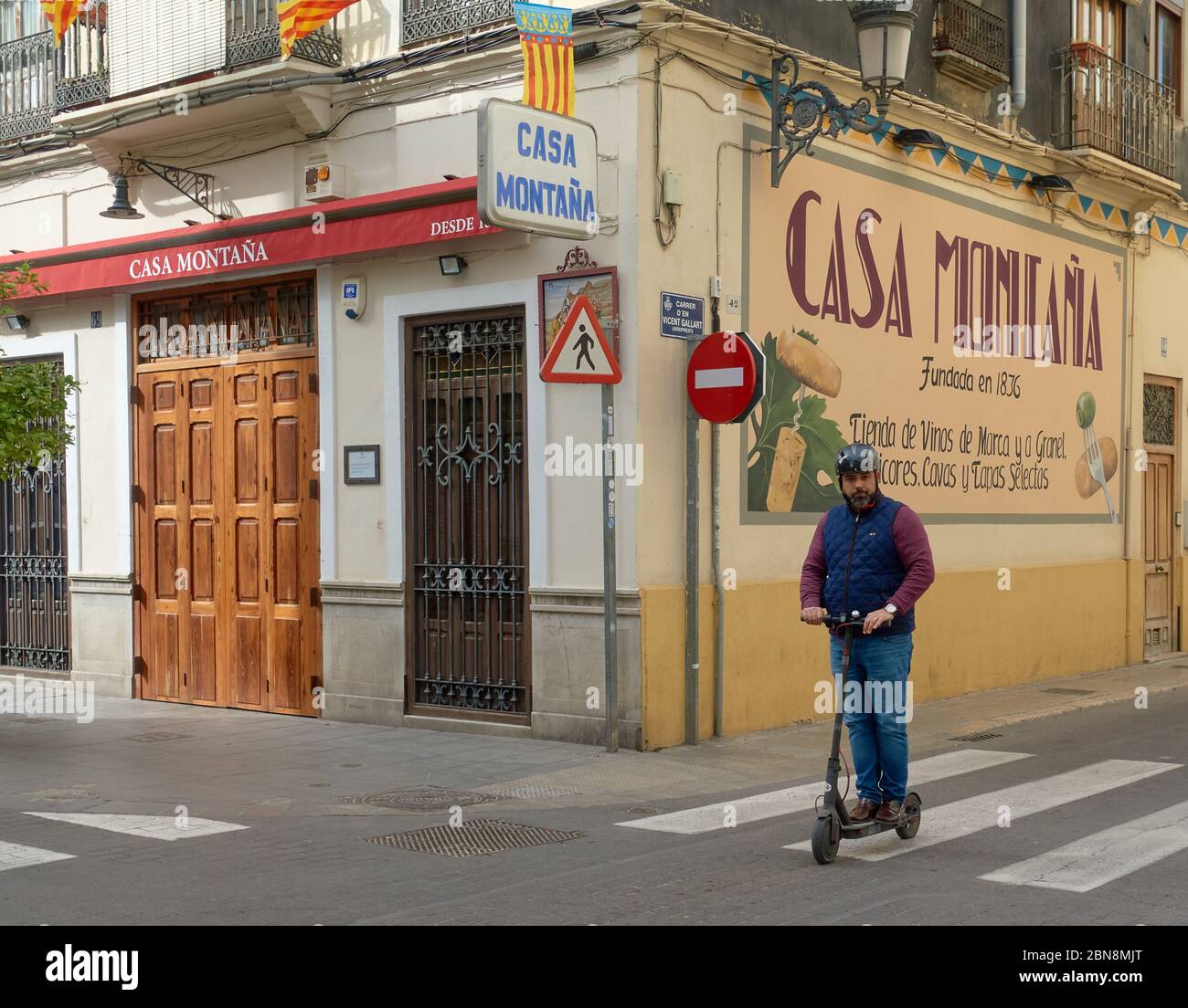 Un homme passe devant le restaurant Casa Montana estimé sur un scooter électrique à El Cabanyal, Valence, Espagne Banque D'Images