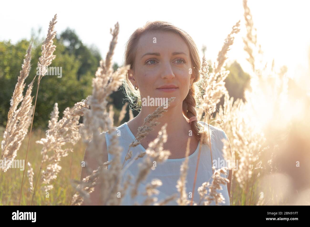 Portrait d'une jolie fille. Jolie blonde avec des yeux bleus. Le soleil du matin brille sur la fille. Banque D'Images