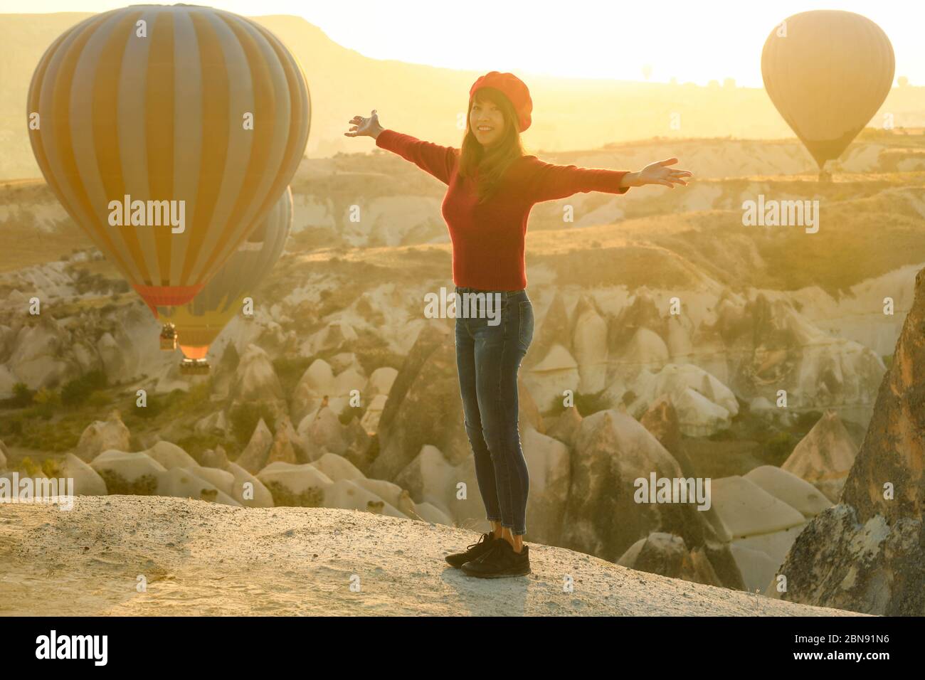 Doux foyer sur la femme asiatique se tenant sur un paysage fantastique avec des ballons d'air chaud dans le premier moning à Cappadoce, Turquie Banque D'Images