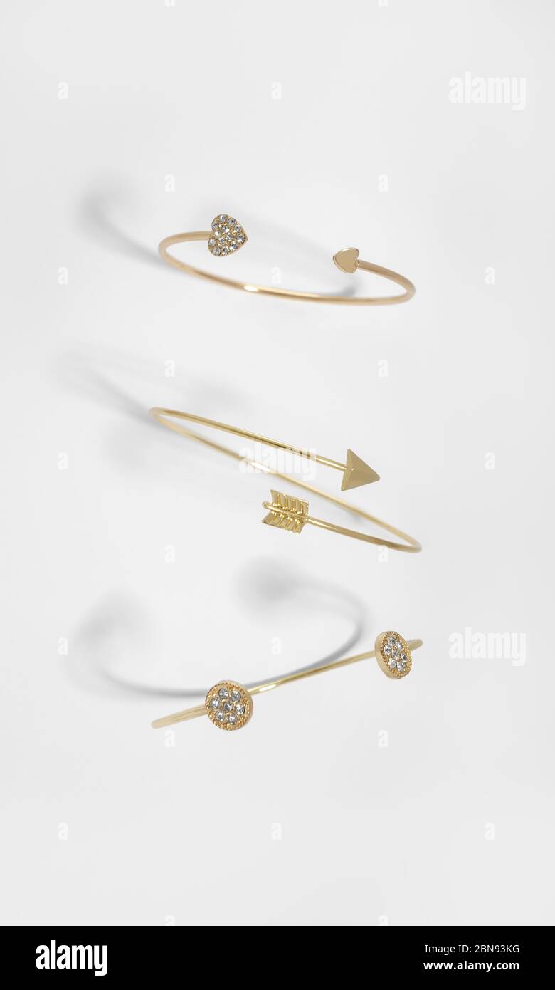 Vue de dessus de trois bracelets dorés de conception différente sur fond blanc Banque D'Images