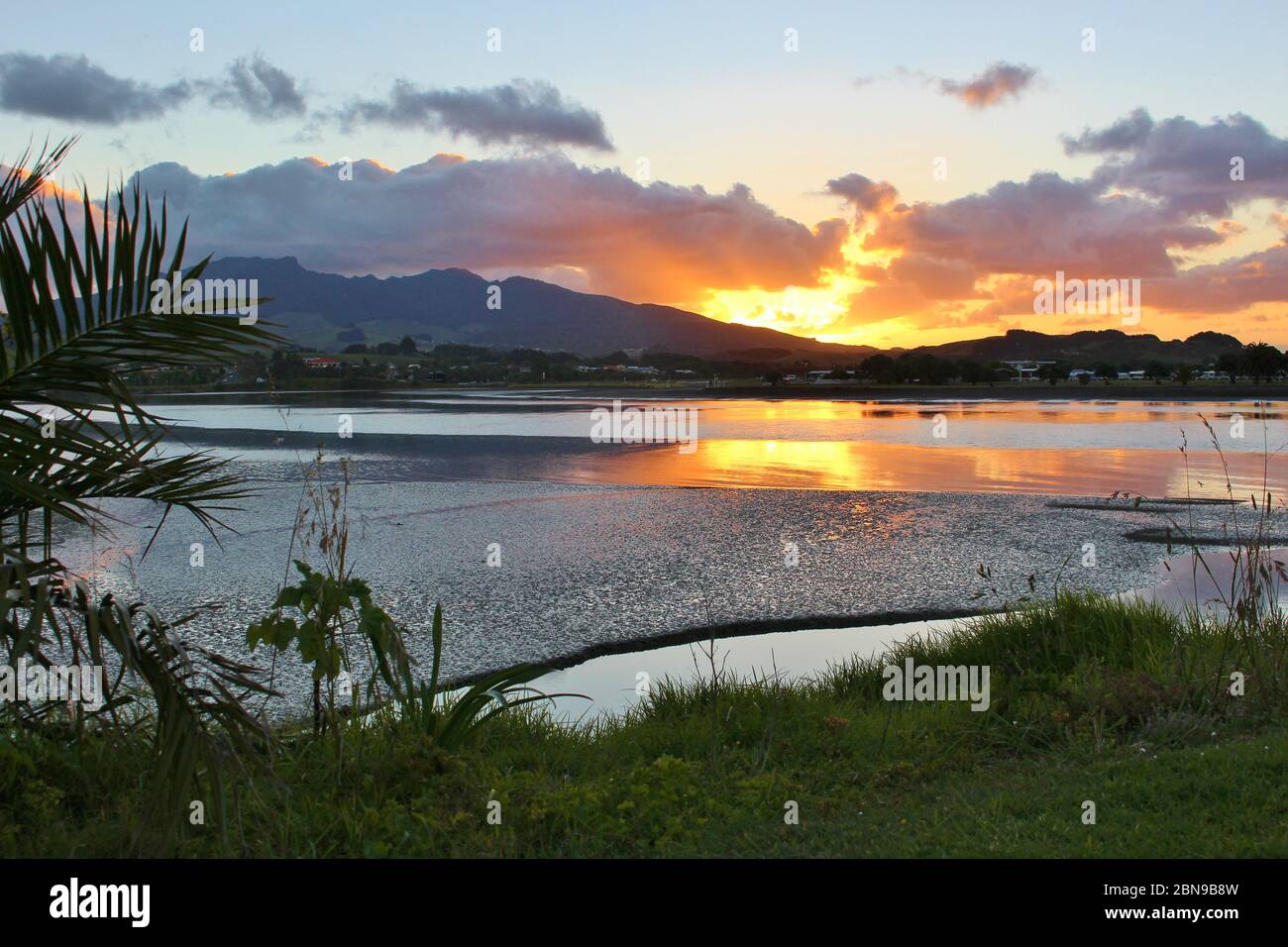 Magnifique coucher de soleil avec ciel spectaculaire sur un lac et une montagne à Raglan en Nouvelle-Zélande. Banque D'Images
