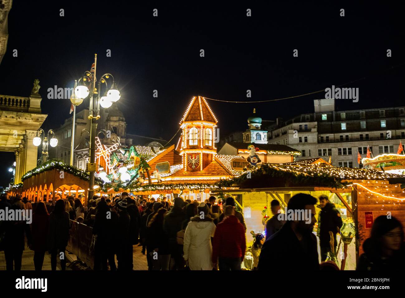 Les amateurs de shopping et de souvenirs apprécient une soirée parmi les huttes illuminées du marché de Noël de Birmingham Banque D'Images