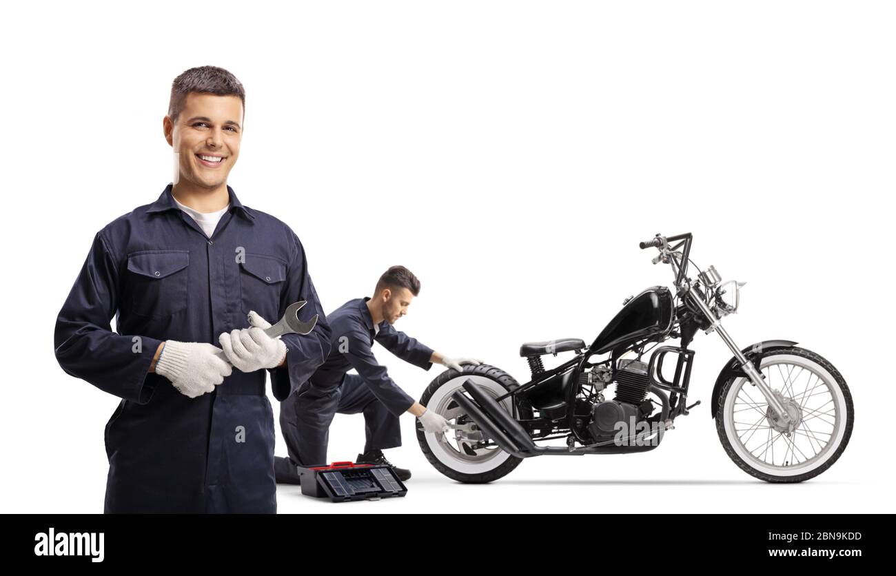 Un mécanicien tenant une clé et posant et autre mécanicien réparant une moto-hachoir isolée sur fond blanc Banque D'Images