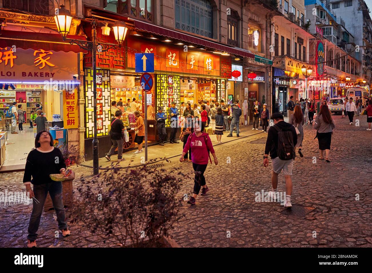 Les personnes marchant dans la rue Rua de S. Paulo (Dasanba) illuminés la nuit. Macao, Chine. Banque D'Images